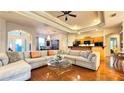 Spacious living room with hardwood floors, tray ceiling, ceiling fan, and an open layout into the dining area at 2158 Fentress Ct, Spring Hill, FL 34609