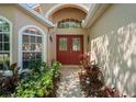 Inviting entryway featuring a double door entrance, arched windows, and lush landscaping at 303 Rochester St, Spring Hill, FL 34609