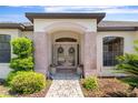 Beautiful front entrance featuring double doors, decorative wreaths, and lush landscaping at 1038 Greenturf Rd, Spring Hill, FL 34608