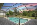 Screened-in pool with beautiful brick pavers and a view of the expansive backyard at 1038 Greenturf Rd, Spring Hill, FL 34608