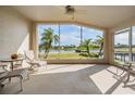 Relaxing sunroom with tile flooring and large windows showcasing serene water views and tropical landscaping at 1809 Westerham Loop, Trinity, FL 34655