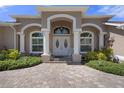 Inviting front entrance featuring elegant double doors, columns, and lush landscaping at 2375 Fairskies Dr, Spring Hill, FL 34606