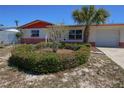 A single-story house with red and white trim, surrounded by lush landscaping and green lawn at 3600 Winder Dr, Holiday, FL 34691