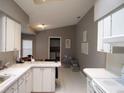 Bright kitchen with white cabinets, white appliances, tile flooring, and view to laundry room at 4096 Everett Ave, Spring Hill, FL 34609