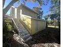 Side view of a yellow home with concrete stairs and lush greenery in the background on a sunny day at 625 25Th S Ave, St Petersburg, FL 33705