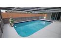 Inviting covered pool featuring a rock waterfall, privacy fence and cool deck at 7024 Coral Reef Dr, Port Richey, FL 34668
