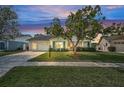 Charming single-story home with a well-manicured lawn and mature tree under colorful evening sky at 9336 Cape Charles Ave, New Port Richey, FL 34655