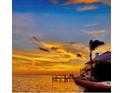 Waterfront property showcasing a long dock and house with an orange sky in the background at 121 Augusta Ave, Palm Harbor, FL 34683