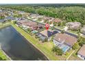 Stunning aerial view of a home with a screened pool, solar panels, and a serene pond in a lush neighborhood at 1709 Nodding Thistle Dr, Trinity, FL 34655