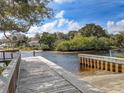 Scenic view of a wooden dock extending into a tranquil river with lush trees and a blue sky background at 1709 Nodding Thistle Dr, New Port Richey, FL 34655