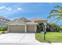 Charming single-story home with a three-car garage, landscaped yard, and beautiful palm trees under a sunny sky at 1709 Nodding Thistle Dr, New Port Richey, FL 34655