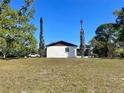 Back exterior view of home with a large yard and mature trees on the property at 6012 Landover Blvd, Spring Hill, FL 34609