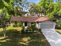 Charming single-story home featuring mature trees, a well-kept lawn, and a two-car garage at 8364 Eldridge Rd, Spring Hill, FL 34608