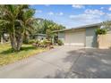 A view of the home's driveway leading up to a two-car garage, surrounded by lush landscaping at 9040 Mark Twain Ln, Port Richey, FL 34668