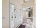 Bright entryway with tile flooring, a glass-paneled sidelight, chandelier, and view to a room with a ceiling fan at 1005 Indigo Run Ct, Spring Hill, FL 34609