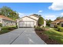 Exterior shot of a well-maintained home with a two-car garage, neat landscaping, and a concrete driveway at 1005 Indigo Run Ct, Spring Hill, FL 34609