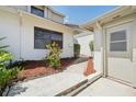 Home's side entrance with mulched landscaping, white door, and trimmed plants at 11735 Rolling Pine Ln, Port Richey, FL 34668