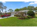 Landscaped front yard with mature tree and vibrant green grass leading to the house at 2309 Terrace View Ln, Spring Hill, FL 34606