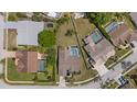 Aerial view of a property featuring a screened pool, fenced yard, and surrounded by lush landscaping at 5412 Merkin Pl, New Port Richey, FL 34655