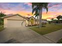 Attractive single-story home with a two-car garage, lush front lawn, and a beautiful sunset backdrop at 5412 Merkin Pl, New Port Richey, FL 34655
