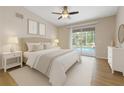 A well-lit main bedroom with a ceiling fan, with sliding glass doors leading to a view of the pool at 5412 Merkin Pl, New Port Richey, FL 34655