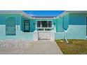 Charming entrance with light blue exterior, a decorative gate, and well-maintained landscaping details at 7221 Westwind Dr, Port Richey, FL 34668