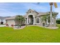 Charming home with a well-manicured lawn, complemented by lush landscaping and mature palm trees at 7511 Melogold Cir, Land O Lakes, FL 34637