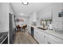Updated kitchen with white cabinets, stainless steel appliances, subway tile backsplash, and a breakfast nook at 1074 Woodbrook S Dr, Largo, FL 33770