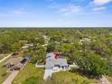 Aerial view of a gray single-story home with a screened-in pool, surrounded by a lush green landscape at 1156 Battersea Ave, Spring Hill, FL 34609