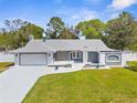 Charming single-story home with a well-manicured lawn, gray exterior, and an attached two-car garage at 1156 Battersea Ave, Spring Hill, FL 34609
