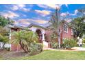 Charming brick home with a well-kept lawn and landscaped garden, complemented by mature palm trees at 1218 Castle Ter, Tarpon Springs, FL 34689
