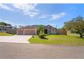Well-maintained single-story home with a spacious three-car garage and lush green lawn at 12300 Drake Ln, Spring Hill, FL 34609