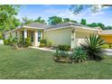 Inviting home exterior featuring lush lawn and garden beds with mature shrubs, complemented by a neutral-toned facade at 14581 Wake Robin Dr, Brooksville, FL 34604