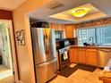 Bright kitchen with stainless steel fridge, natural wood cabinets, and tile flooring and countertops at 2349 Holston Ave, Spring Hill, FL 34608