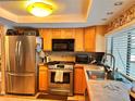 Bright kitchen featuring stainless steel appliances, tile countertops, and ample cabinet space at 2349 Holston Ave, Spring Hill, FL 34608