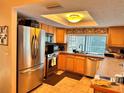 Well-lit kitchen with stainless steel refrigerator, oven, microwave, and a window above the sink at 2349 Holston Ave, Spring Hill, FL 34608