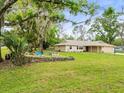 Inviting single-story home with a well-manicured lawn, mature trees, and charming landscaping at 24104 Peppermill Dr, Brooksville, FL 34601