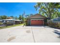 Home exterior with a green paint scheme, red garage door, boat cover, mature trees, and a driveway at 28330 Peterson Camp Rd, Brooksville, FL 34601