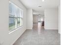 Bright hallway showcasing neutral tile flooring, access to different rooms, and a view to the backyard at 30839 Penny Surf Loop, Wesley Chapel, FL 33545