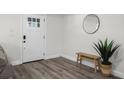 Inviting entryway featuring wood-look floors, a bench, a round mirror, and a bright front door at 3416 Lema Dr, Spring Hill, FL 34609
