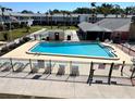 Community swimming pool featuring fenced in area, pool furniture and shade, surrounded by green landscaping at 4653 Cambridge Ave # 4653, New Port Richey, FL 34652