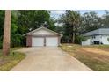 A two-car garage featuring brick accents and a long driveway bordered by mature trees and green space at 5417 Carlton Rd, New Port Richey, FL 34652