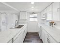 Bright kitchen featuring white cabinetry, modern appliances, marble countertops, and wood-look flooring at 6422 Tralee Ave, New Port Richey, FL 34653