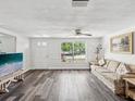 Bright living room features wood-look flooring, a large window and a comfortable sofa and decor at 6422 Tralee Ave, New Port Richey, FL 34653
