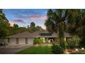 Charming single-story home featuring a three-car garage, well-manicured lawn, and tropical landscaping at 6475 Laurel Oak Dr, Spring Hill, FL 34607