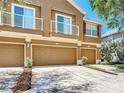 Elegant tan townhome with a multi-car garage and balcony for a scenic elevated view at 6821 Breezy Palm Dr, Riverview, FL 33578