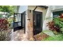 Enclosed front entrance with brick accents, mature plants, and tiled pathway at 7495 Heather Walk Dr, Weeki Wachee, FL 34613