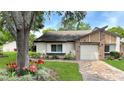 Well-maintained home with manicured lawn, colorful flower bed, and brick-accented attached garage at 7495 Heather Walk Dr, Weeki Wachee, FL 34613
