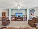 Inviting living room with comfortable seating, a ceiling fan, and a view into another room at 11050 Kiskadee Cir, New Port Richey, FL 34654