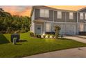 Charming townhome with well-manicured lawn and landscape is illuminated by the sunset and outdoor lighting at 12214 Grizzly Ln, New Port Richey, FL 34654